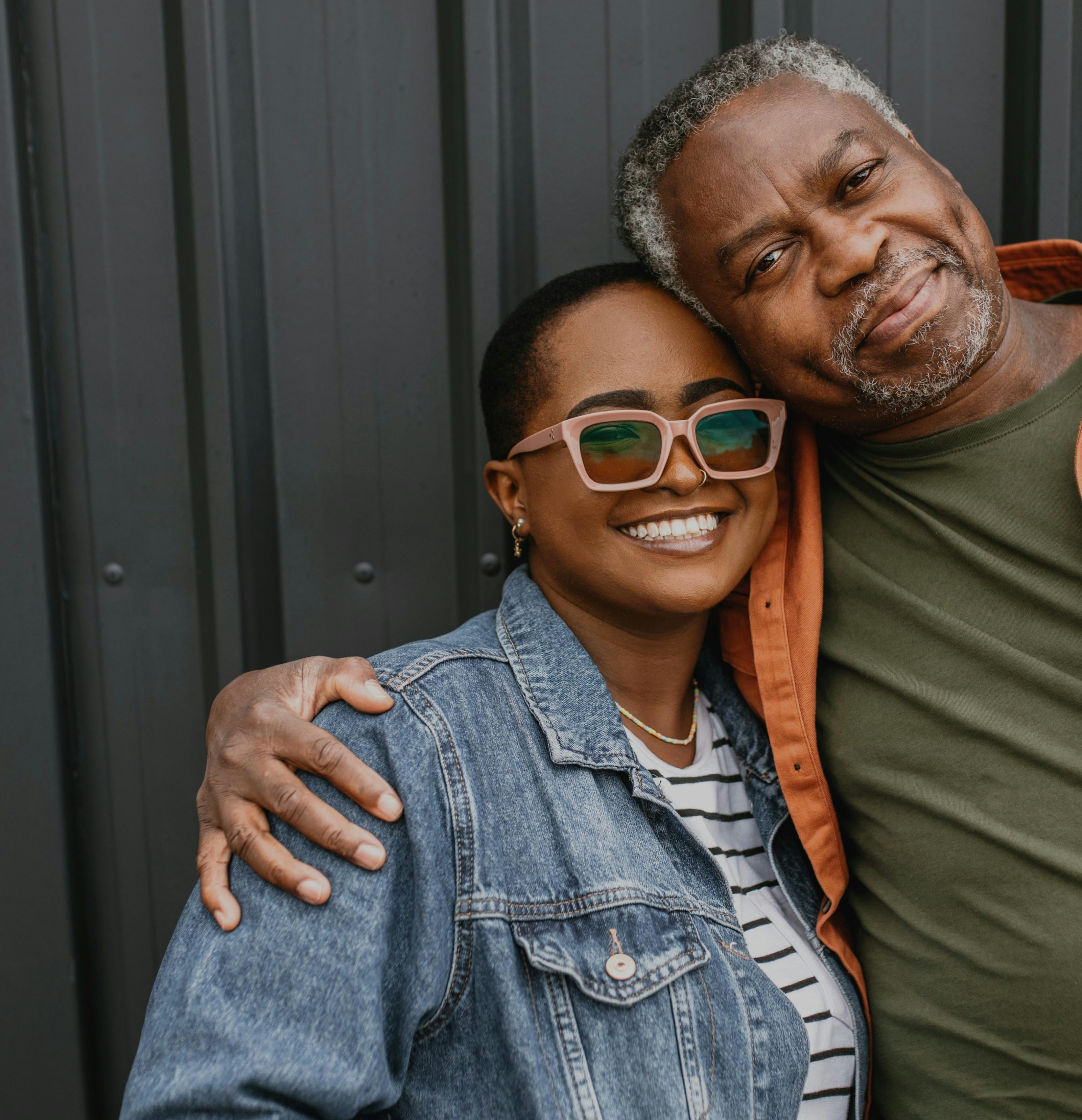 A photo of a man and woman smiling in a side hug looking at the camera.